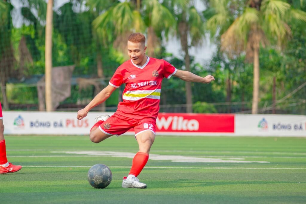 Energetic soccer match with young player in action on a sunny day in Hanoi.