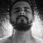 Artistic black-and-white portrait of a bearded man enjoying a refreshing shower.